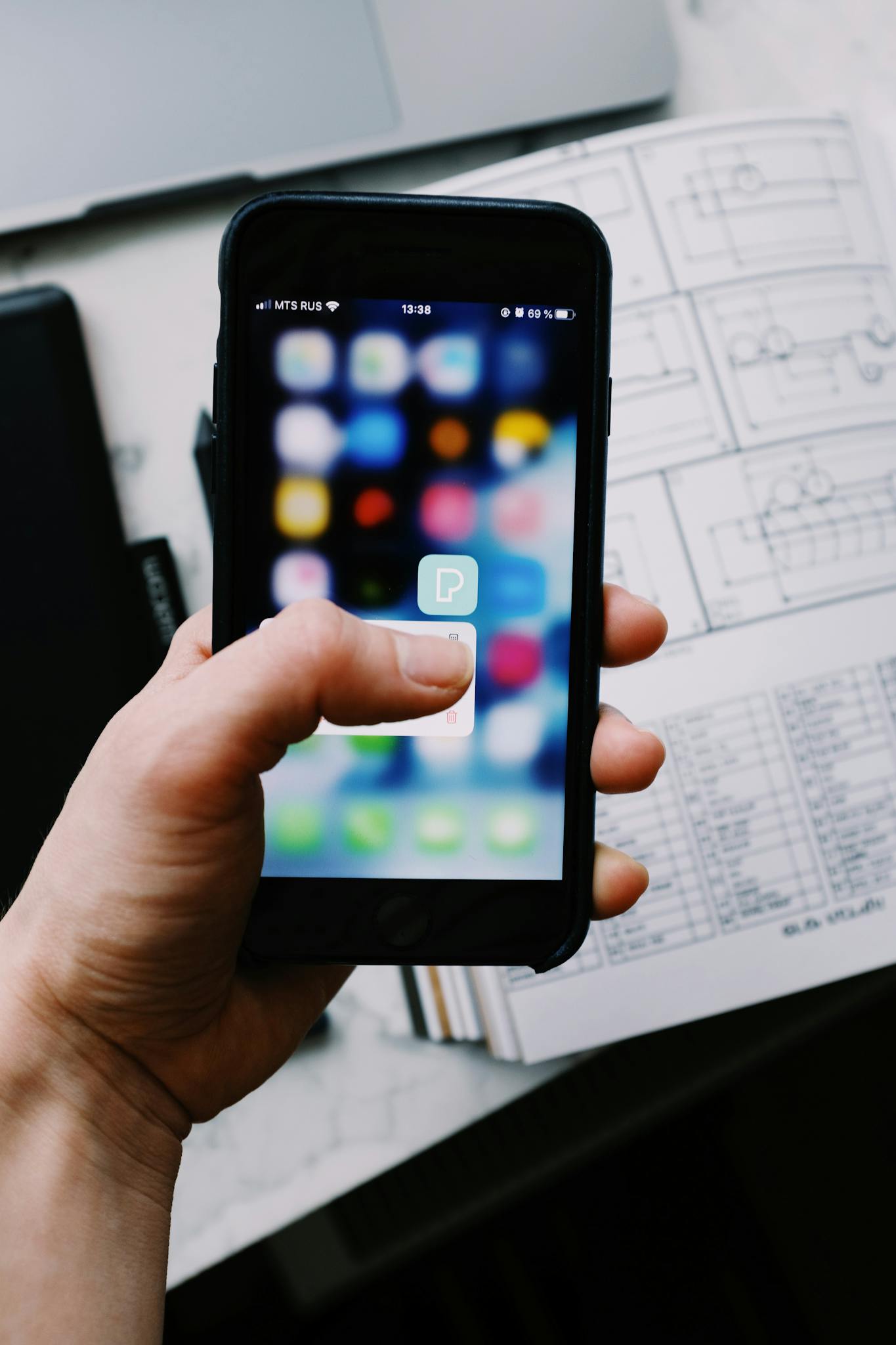 Close-up of a hand holding a smartphone with a visible app icon on screen.