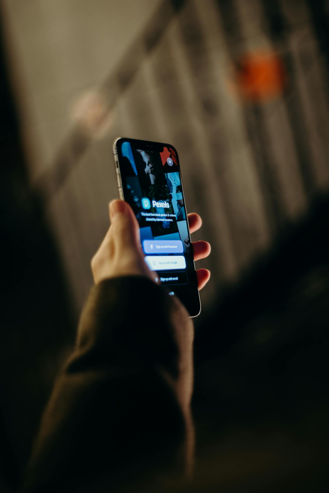 Close-up of a hand holding a smartphone displaying a login interface. Blurred background.